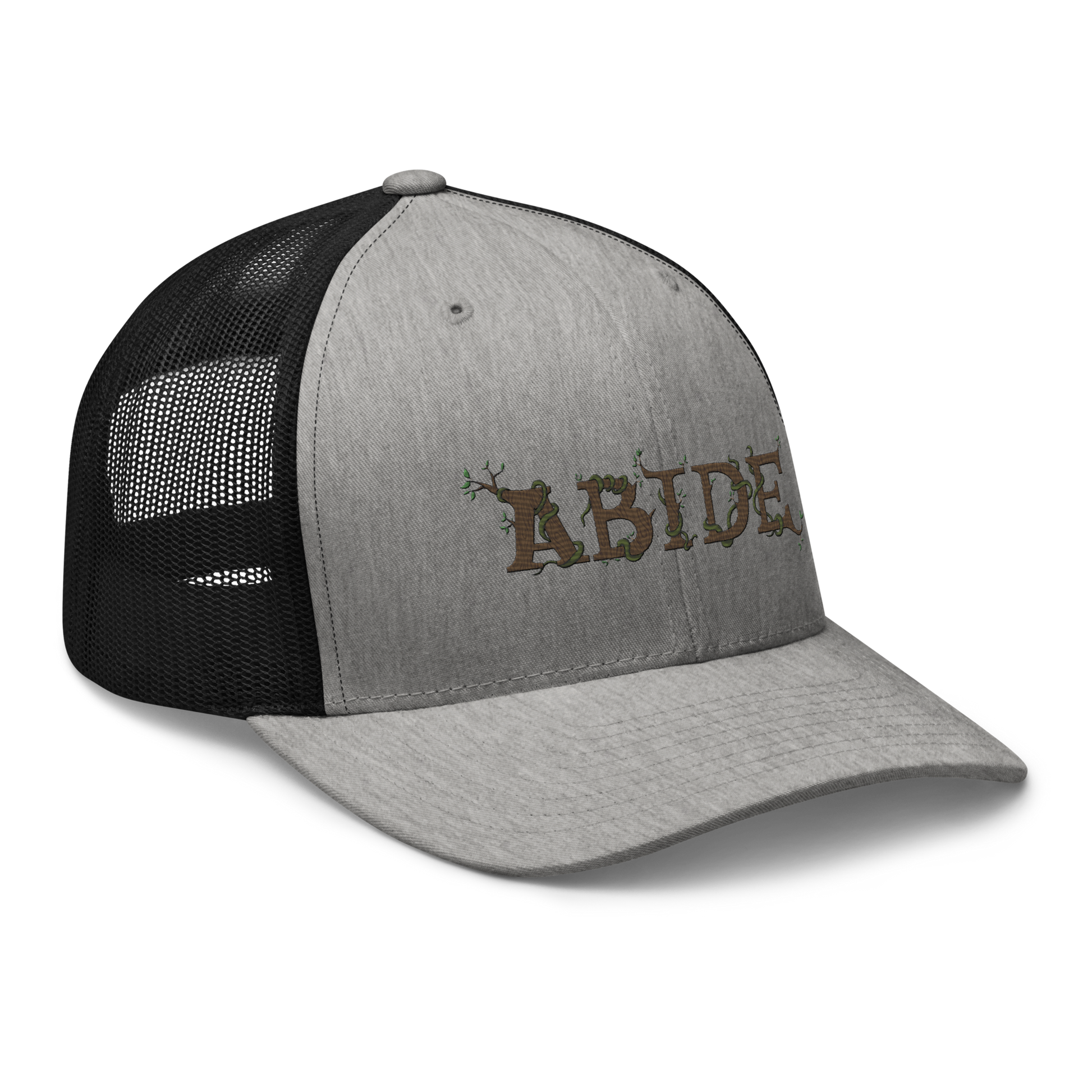 Grey trucker hat with black mesh with the letters Abide on the front. The letters are in brown with green vines wrapped around. The Abide is embroidered on the hat.