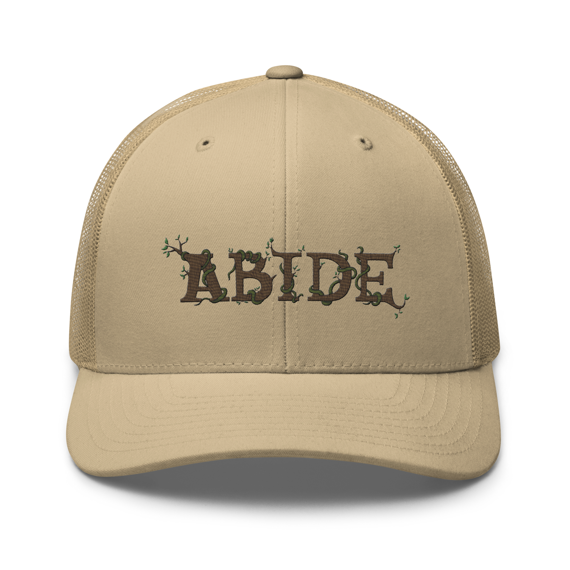 Desert tan trucker hat with the letters Abide on the front. The letters are in brown with green vines wrapped around. The Abide is embroidered on the hat.