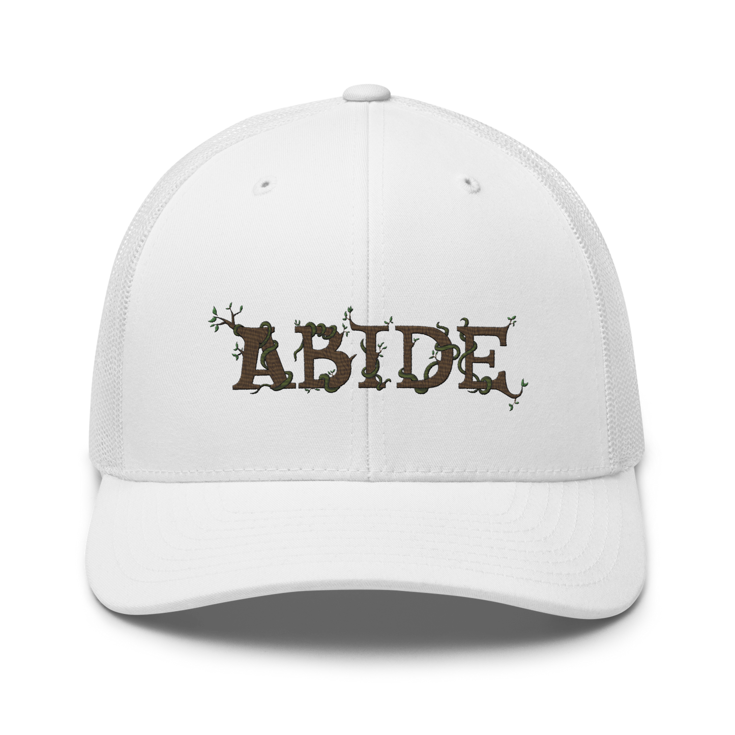 White trucker hat with the letters Abide on the front. The letters are in brown with green vines wrapped around. The Abide is embroidered on the hat.