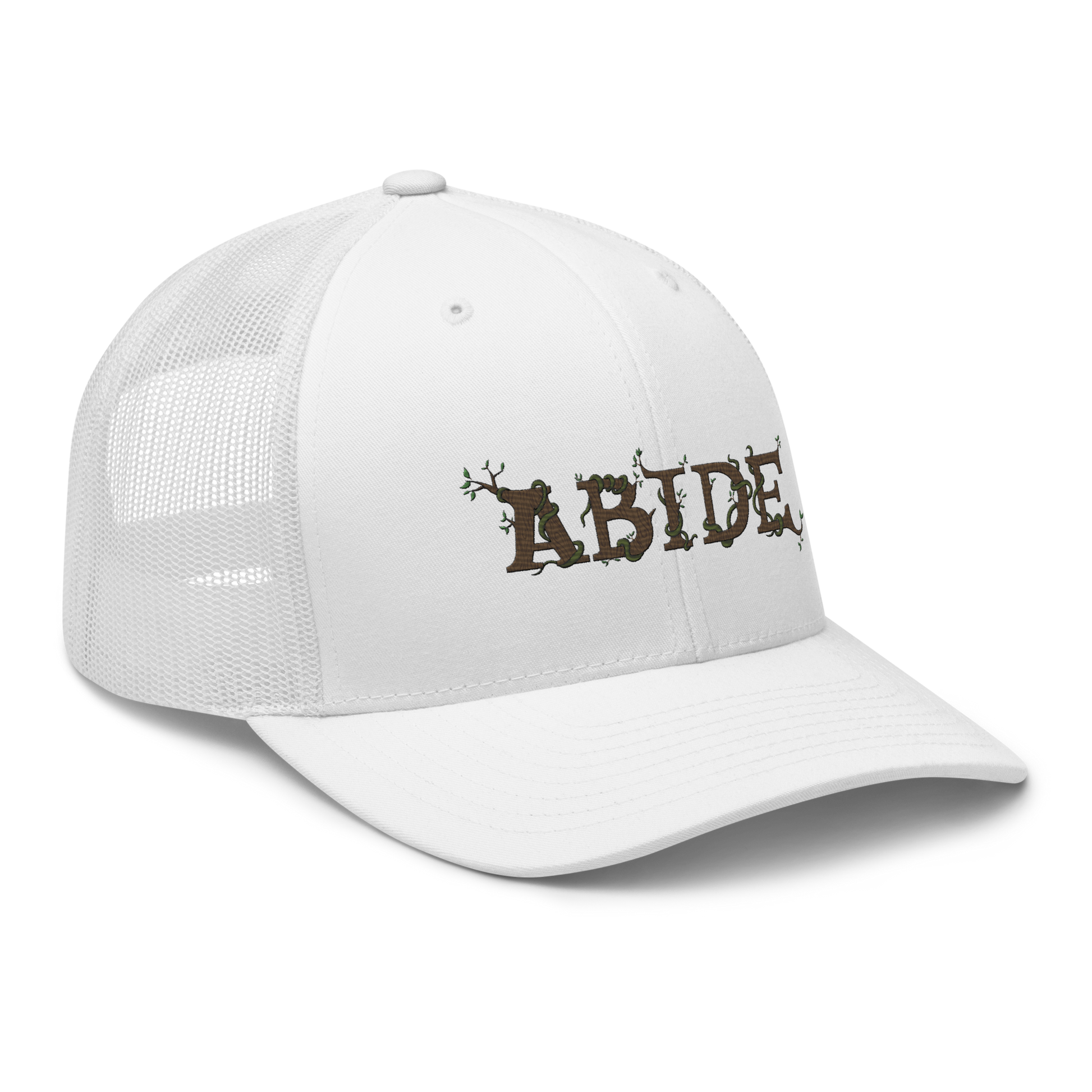 White trucker hat with the letters Abide on the front. The letters are in brown with green vines wrapped around. The Abide is embroidered on the hat.